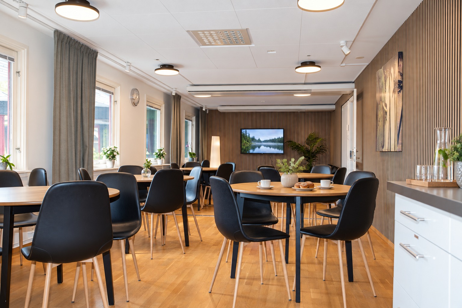 Café och gemensam matplats med bord, kaffestation och träpanel